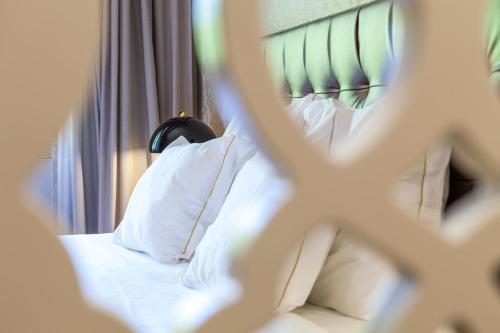 a bed with a green headboard and white pillows at Hotel Lis Batalha in Batalha