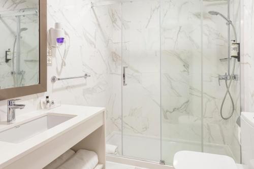 a white bathroom with a shower and a sink at Hotel Lis Batalha in Batalha