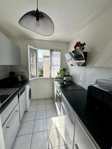 une cuisine blanche avec un comptoir noir dans l'établissement Jessi home, à Limeil-Brévannes