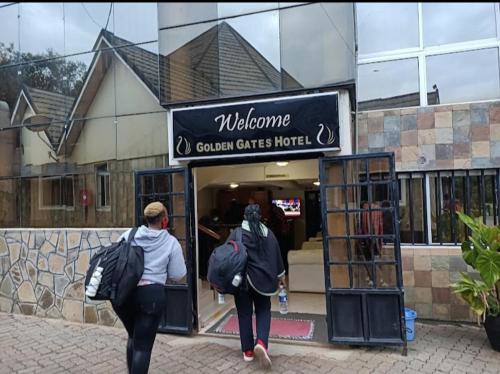 two people with backpacks walking out of a store at Golden Gates Hotel in Mweiga