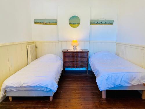 - 2 lits dans une chambre avec une commode et une lampe dans l'établissement Charmante maison authentique, proche bassin, à Arès
