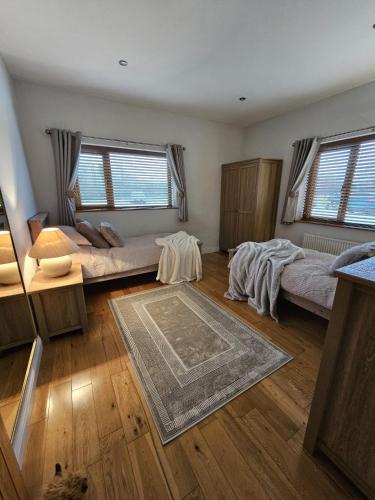 a living room with two beds and a rug at Lakefront Lodge with Hot Tub - Aylesbury Lodge in Shepton Mallet