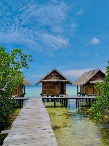 a row of huts on a dock in the water at Mares Homestay-Raja Ampat in Fam
