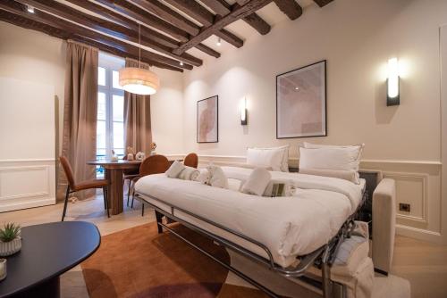 - un grand lit dans une chambre avec une table et des chaises dans l'établissement Appartement de luxe d'une chambre près du Louvre II, à Paris