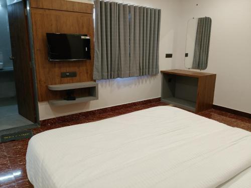 a bedroom with a bed and a flat screen tv at Dwarka Dekho - Grand Palace in Dwarka