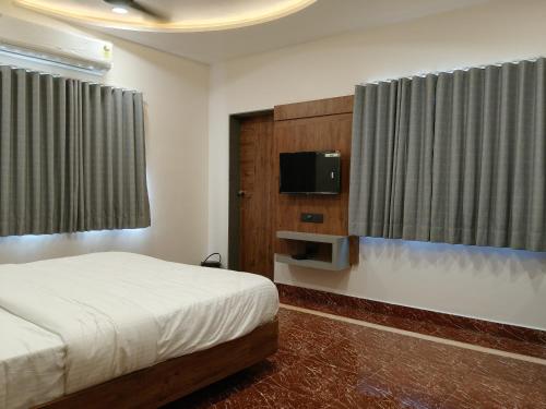 a bedroom with a bed and a flat screen tv at Dwarka Dekho - Grand Palace in Dwarka