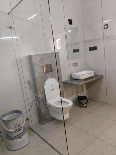 a bathroom with a toilet and a glass shower at Dwarka Dekho - Grand Palace in Dwarka
