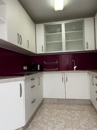 a kitchen with white cabinets and purple walls at La casa de Elisabeth in Nerja