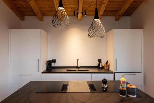a kitchen with white cabinets and a sink and pendant lights at Colago Private Villas Lake Garda in Toscolano Maderno