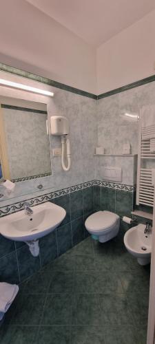 a bathroom with two sinks and a toilet at Hotel Riviera 3 Stelle con piscina estiva gratuita e garage a pagamento in Spotorno