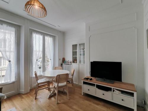 un salon avec une table et une télévision dans l'établissement L'hermine, à Saint-Malo