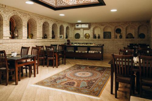 Un restaurante con mesas y sillas y una pared de ladrillos. en Boutique Hotel Shakhrut, en Bukhara