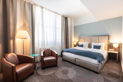 a hotel room with a bed and a chair at Garner Hotel Essen - Handelshof by IHG in Essen