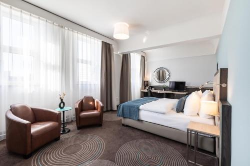 a hotel room with a bed and a chair at Garner Hotel Essen - Handelshof by IHG in Essen