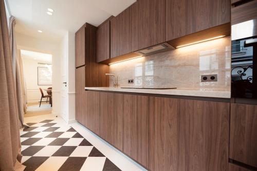 - une cuisine avec des placards en bois et un sol en damier dans l'établissement Appartement de luxe d'une chambre à proximité du Louvre III, à Paris