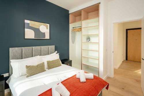 a bedroom with a large white bed with an orange blanket at Chiswick Parkside Apartments by Sleepy Lodge London in Kew Bridge
