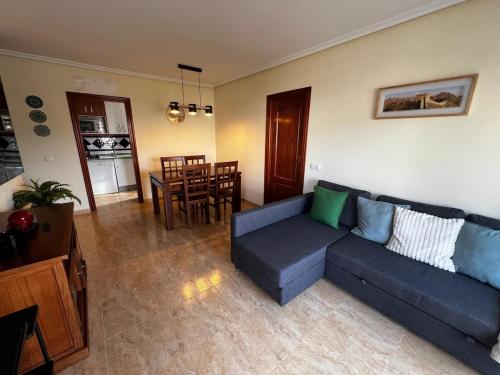 a living room with a blue couch and a dining room at Spectacular Flat Vera Playa in Playas de Vera