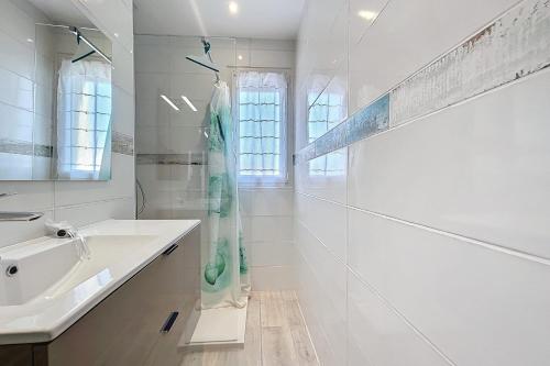 Un baño blanco con lavabo y ducha. en Spacious cocoon in Narbonne - with sea view, en Narbona