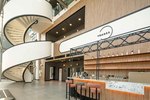 a shopping mall with a spiral staircase and stools at Chiswick Parkside Apartments by Sleepy Lodge London in Kew Bridge