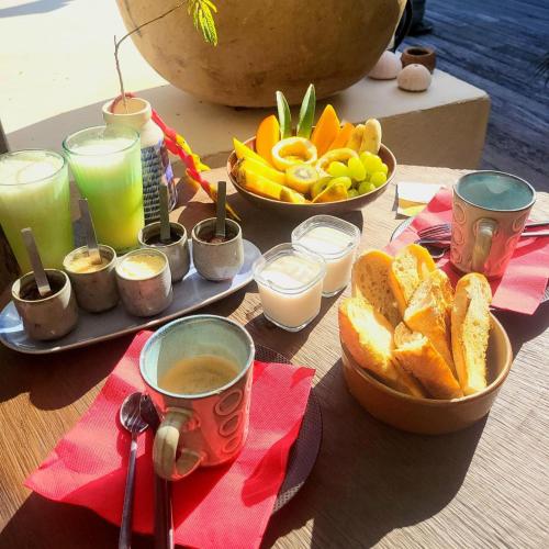 a table with cups of coffee and bread and drinks at Marie Galante CHAMBRE CHEZ L HABITANT petit déjeuner sur demande in Saint-Louis