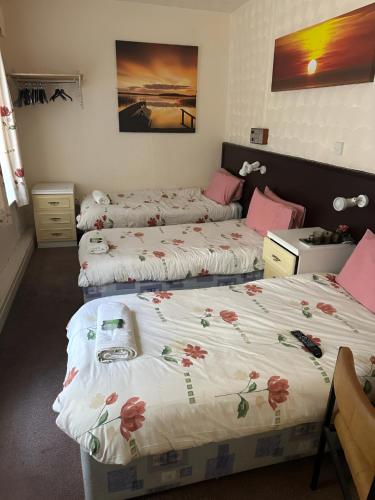 a room with two beds with flowers on them at Balin Helmshore in Blackpool