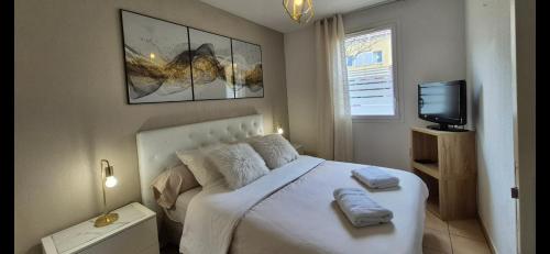 a bedroom with a white bed and a television at A 500 mètres des plages et du port du brusc, Les terrasses des embiez avec piscine et spa in Six-Fours-les-Plages