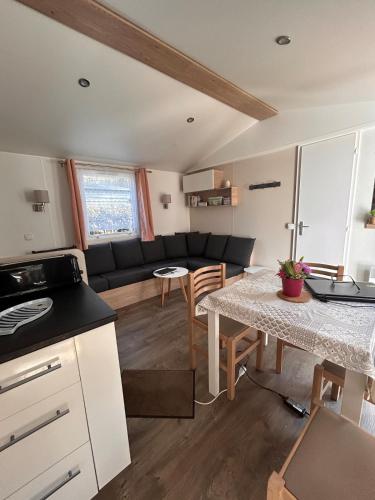 une cuisine et un salon avec une table et un canapé dans l'établissement Mobilhome Calme 6 Personnes Camping Pierre Couché, à Saint-Brévin-les-Pins