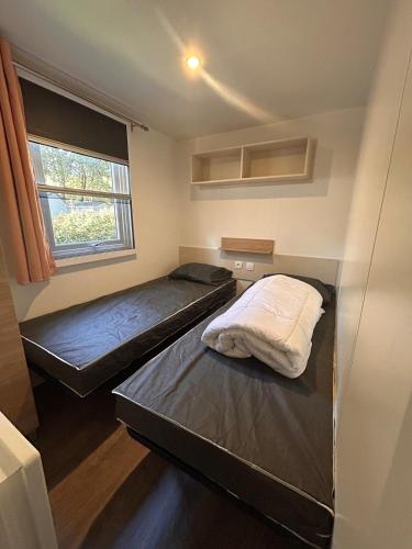 zwei Betten in einem kleinen Zimmer mit Fenster in der Unterkunft Mobilhome Calme 6 Personnes Camping Pierre Couché in Saint-Brevin-les-Pins