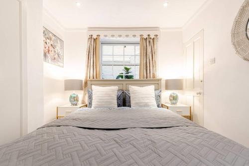 a white bedroom with a large bed and a window at Secluded Modern Private Apartment by Buckingham Palace in London