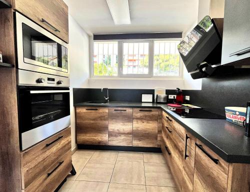 une cuisine avec des armoires en bois et un comptoir noir dans l'établissement L'aiglon, à Cassis