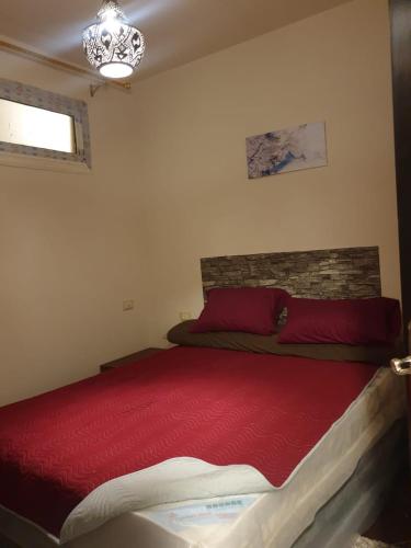 a bedroom with a bed with red sheets and a chandelier at Porto Matrouh Unique Chalet 73004 in Marsa Matruh