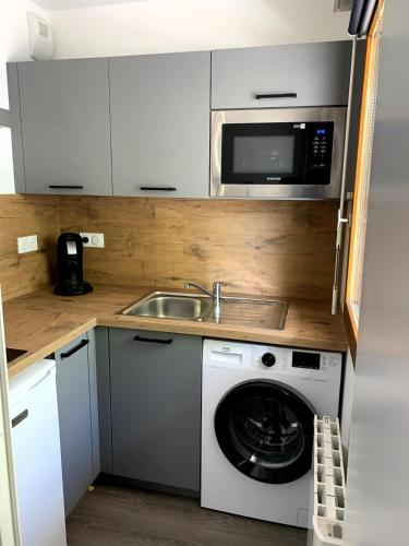 une cuisine avec un lave-linge et un micro-ondes dans l'établissement Appartement T1 proche aéroport, à Saint-Jacques-de-la-Lande