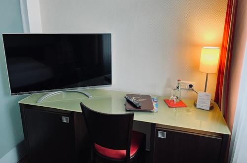 a desk with a television and a chair in a room at Maris Hotel in Steinhude