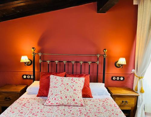 a bedroom with a bed with an orange wall at La Cuestecilla in Hervás