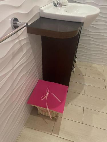 a bathroom with a sink and a pink sign on the floor at Hosteria Las Fuentes in Rubayo
