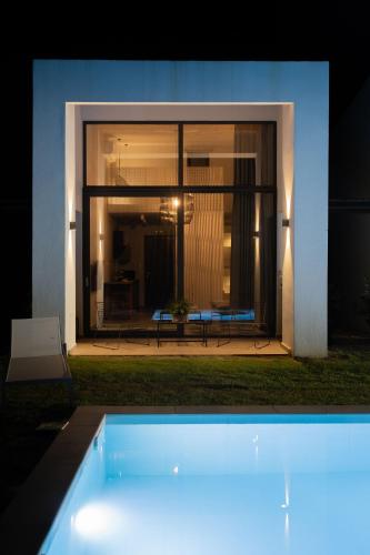 a swimming pool in front of a house at night at Sevene Villas - Kourouta Peloponnese in Petroúlai