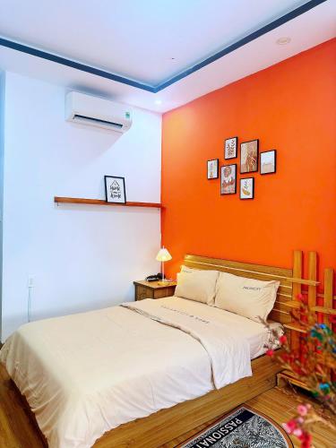 a bedroom with a white bed and an orange wall at Homestay Homie House in Liên Trì (3)