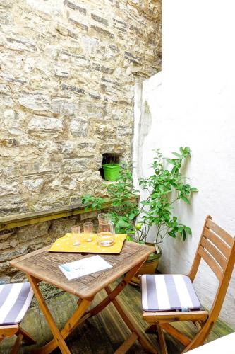 une table en bois avec deux chaises à côté d'un mur en pierre dans l'établissement Biarritz 2 pièces en hypercentre, tout à pied, à Biarritz