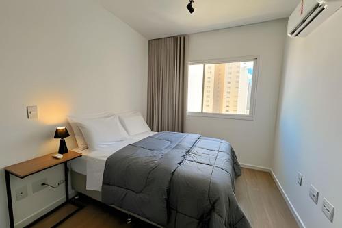 a small bedroom with a bed and a window at Moderno apto - vista maravilhosa in Londrina