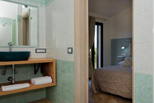 a bathroom with a sink and a mirror and a bed at B&B Tiscali in Dorgali