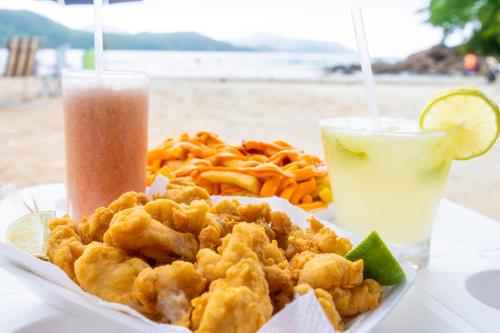 a plate of food with shrimp and fries and a drink at Mar e Praia Hotel in Ubatuba