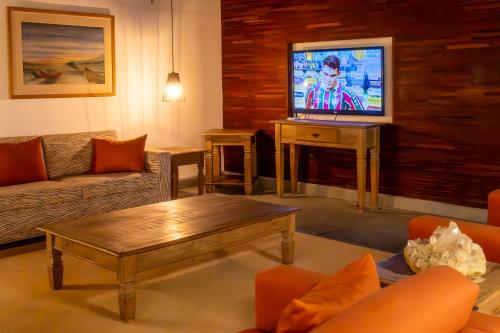 a living room with a couch and a tv at Mar e Praia Hotel in Ubatuba