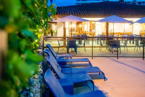a row of blue benches on a patio with tables and umbrellas at Mar e Praia Hotel in Ubatuba