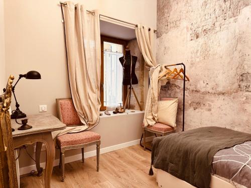 une chambre avec un lit, un bureau et une fenêtre dans l'établissement Le Tailleur, centre historique, fibre, climatisation, ESS, rez-de-chaussée, BedinShop, à Romans-sur-Isère