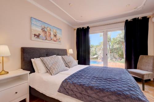 ein Schlafzimmer mit einem Bett und einem Stuhl und einem Fenster in der Unterkunft Villa Mariposa in La Cala de Mijas