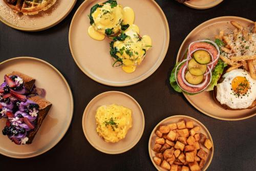 a table with plates of breakfast foods on them at The ENGLiSH Hotel, Las Vegas, a Tribute Portfolio Hotel in Las Vegas