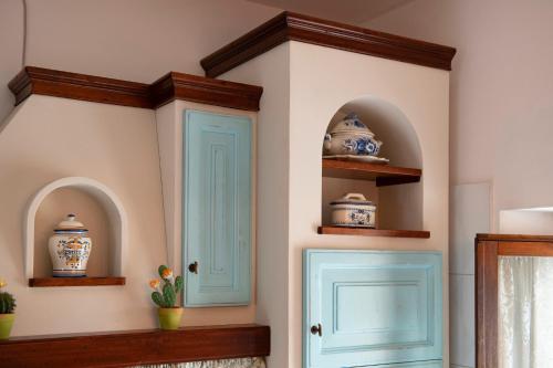 een kamer met turquoise deuren en planken met vazen bij Bellavista free parking city center in San Gimignano