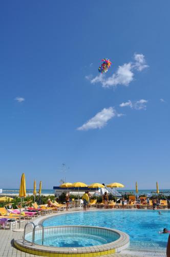 a kite flying in the sky over a swimming pool at Hotel David in Cesenatico