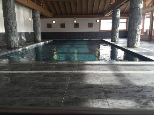 - une piscine avec piliers dans un bâtiment dans l'établissement Superbe 2 pièces neuf avec piscine, parking couvert et Wi-Fi - FR-1-293-244, à Villard-sur-Doron