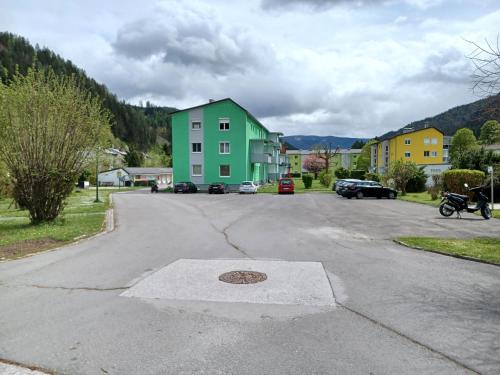 a street with a green house and a parking lot at Bergmann Apartment Veitsch in Niederaigen